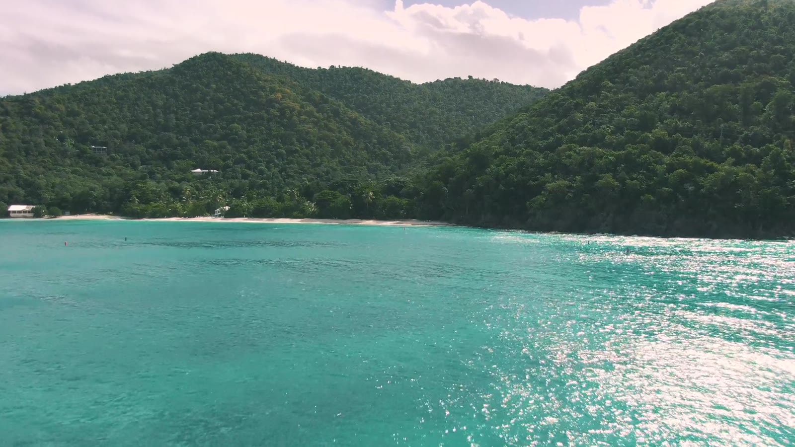 Baie turquoise et mornes verts sous le soleil des Caraïbes